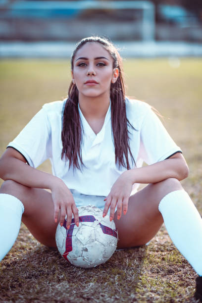 istock Beautiful Female Soccer Posing While Sitting With The Ball Between Her Legs 1124700045