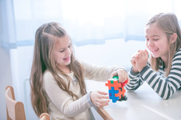 istock Schoolgirls on a Break Playing with Block Puzzle 1124700249