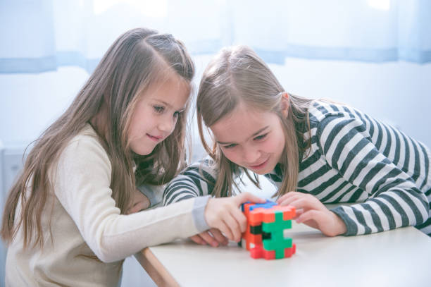 istock Schoolgirls on a Break Playing with Block Puzzle 1124700253