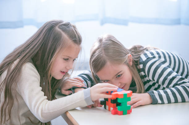 istock Schoolgirls on a Break Playing with Block Puzzle 1124700256