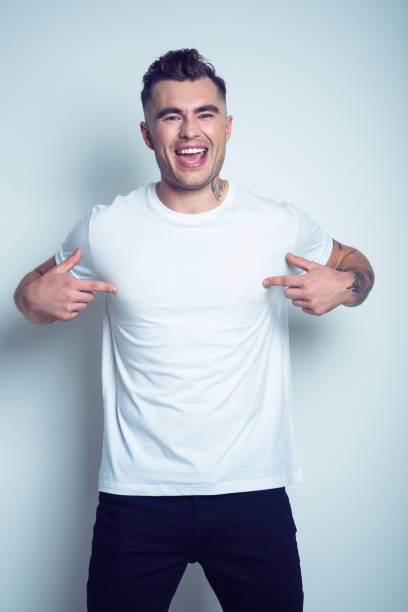 retrato de hombre joven tatuada señalando en camiseta blanca - peinado desarreglado fotografías e imágenes de stock