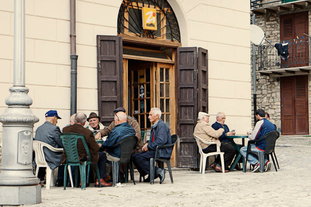 Traditional view of Italian old men sitting in an outdoor cafe, playing cards, drinking coffee and chatting. stock photo