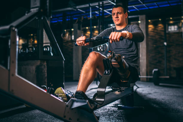 istock Young disabled athlete with a prosthetic leg doing rowing exercises on a machine in a gym arena in a gym 1124701923