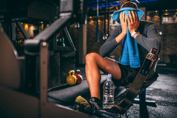 istock Disabled young athlete with a prosthetic leg wiping his face with a towel after a pulling exercise on a rowing machine in a gym gym 1124702016