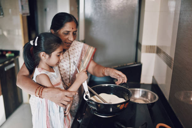 istock Young girl helping her grandmother while working in the kitchen 1124704660