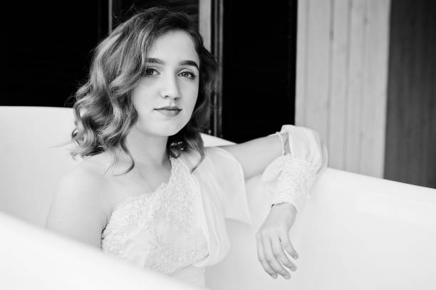 istock Pretty young curly gilrl in white dress sitting at bath. 1124706296