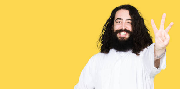 istock Man wearing Jesus Christ costume showing and pointing up with fingers number three while smiling confident and happy. 1124706488