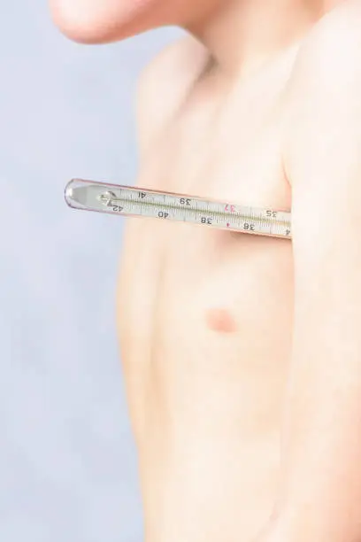 Photo of The body of a small boy, who holds a thermometer at hand and measures the body