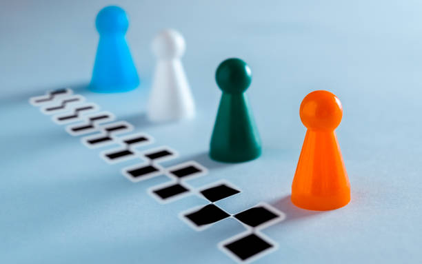 istock Group of four colored board game pawns lined up at the finish line 1124710836