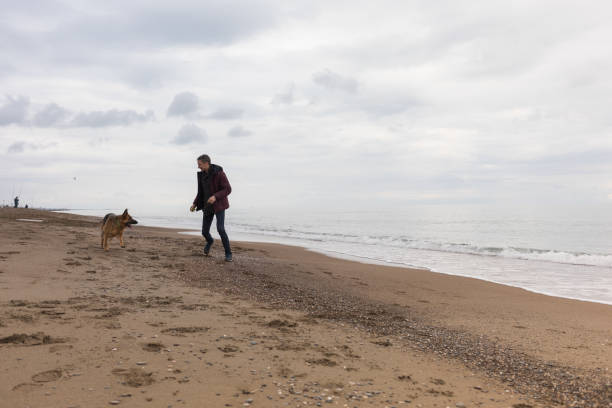 istock Young Man And His Dog On Beach 1124712312