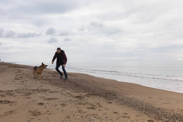 istock Young Man And His Dog On Beach 1124712614
