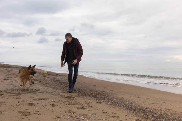 istock Young Man And His Dog On Beach 1124714135