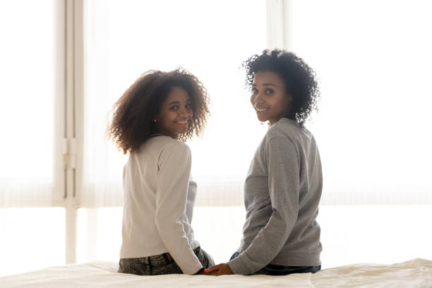 istock Smiling black mom and daughter sit on bed posing 1124715216