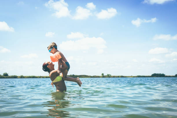 陽気な母と息子水でビーチで楽しんで。 - summer swimming beach vacations ストックフォトと画像