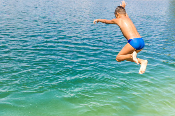 istock Playful boy jumping in the water during summer day. 1124717237