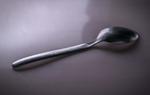 Una cuchara de té de acero colocada sobre una superficie metálica reflectora photo