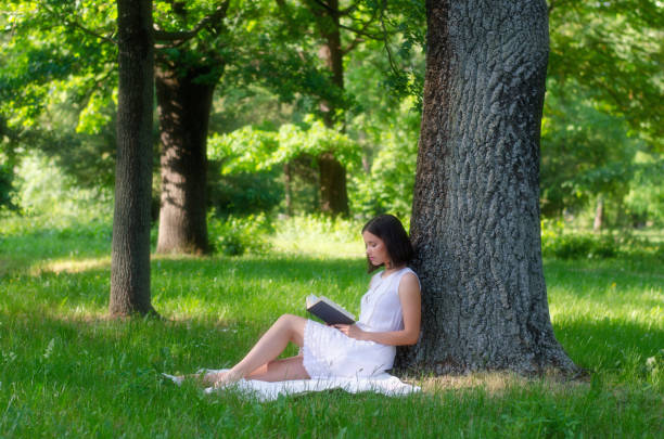 istock Young woman reading book in the summer nature 1124719829