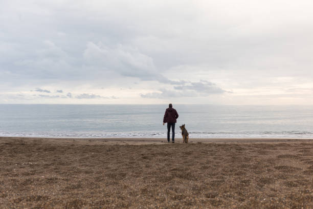 Young man playing with his dog on beach.