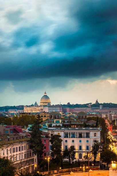 View of the city of Rome at sunset with a storm on the dome of St. Peter's Basilica in Vatican stock photo