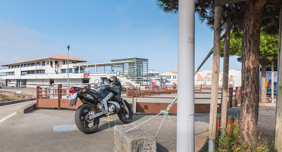 Yeu island, France - September 18, 2018: Motorcycle parked in harbor port Joinville near boats on a summer day