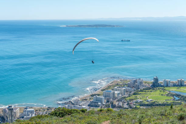 Tandem paraglider after launch from Signal Hill Cape Town, South Africa, August 9, 2018: A tandem paraglider moments after launch from Signal Hill in Cape Town in the Western Cape Province. Green Point and Robben Island are visible signal hill stock pictures, royalty-free photos & images