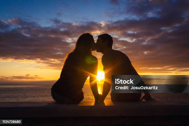 Photo libre de droit de Homme Et Femme Assise Au Bord De La Mer Sembrasser Au Coucher Du Soleil Au Pied De La Plage De Meloneras Gran Canaria banque d'images et plus d'images libres de droit de Tous types de couple