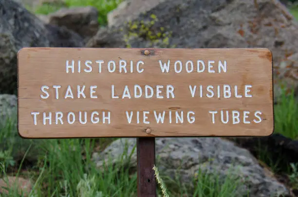 Sign at Devil’s Tower National Monument reading Historic Wooden Stake Ladder Visible through viewing tubes