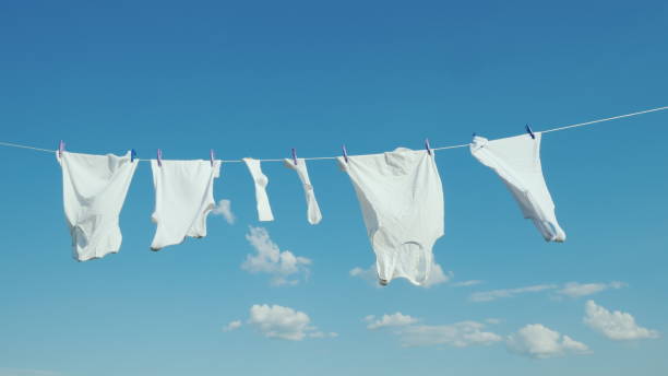 white linen dries on the rope against the blue sky - white clothing imagens e fotografias de stock