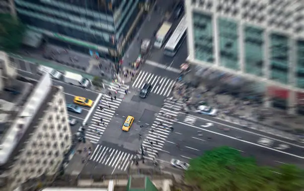 Photo of New York city street full of taxis, cars and pedestrians. Yellow cab in focus. Busy NYC Downtown. Crowd of people crossing crosswalks. Traffic jam in NY.