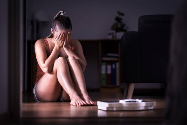 frau, die stress über gewichtsverlust, diät oder gewichtszunahme. eating disorder, anorexie oder bulimie konzept. junges mädchen weint und sitzen auf dem boden mit skala. - bulimia stock-fotos und bilder