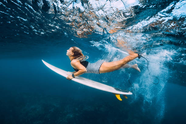 istock Attractive surfer woman with surfboard dive underwater with under wave. 1124733420