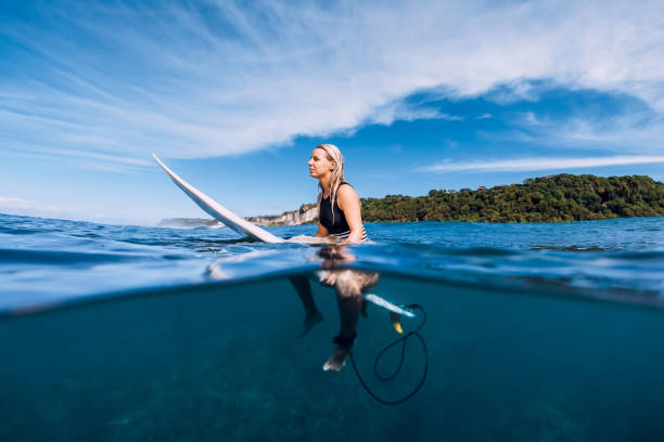 istock Attractive surfer girl at surfboard in ocean 1124733452