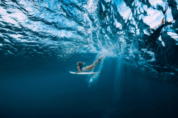 mujer de surf con buceo tabla de surf bajo el agua con bajo de la onda. - surfing surf wave extreme sports fotografías e imágenes de stock