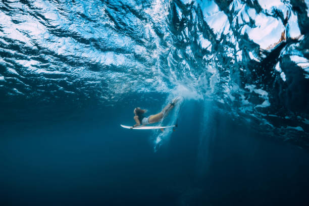 surf женщина с доской для серфинга погружение под водой с под волной. - surfing surf wave extreme sports стоковые фото и изображения