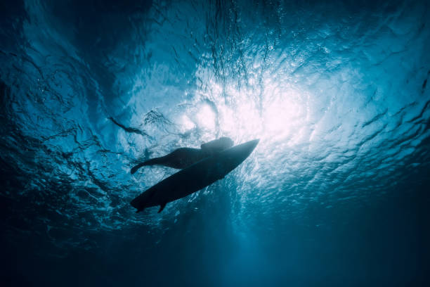 istock Surfer girl with surfboard dive underwater with under ocean wave. 1124734510