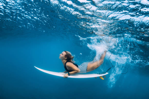 istock Attractive surfer woman dive underwater with under blue wave. 1124734559
