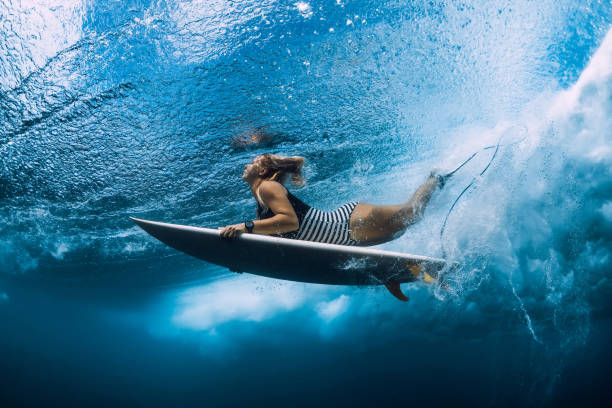 istock Surfgirl with surfboard dive underwater with under ocean wave. 1124734795