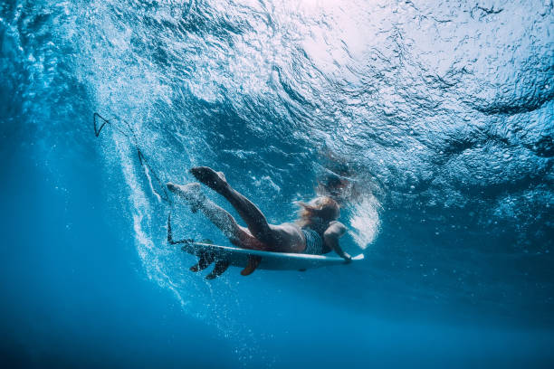 istock Surfer girl with surfboard dive underwater with fun under wave. 1124735187
