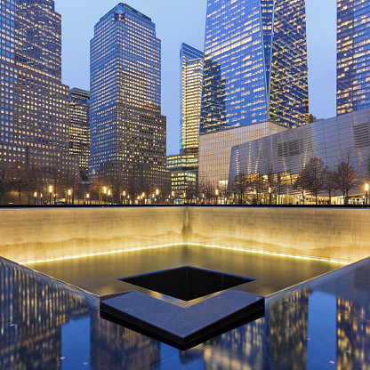 New York City, USA - February 1, 2018: Night time view of Manhattan skyscrapers and the reflecting pools of National September 11 Memorial commemorating the 9/11 attacks and the 1993 World Trade Center bombing. It is located at ground zero where the former World Trade Center twin towers originally stood.
