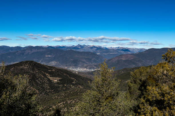 istock Solid blue sky on a mountain range landscape with some clouds on a green winter scene 1124742022