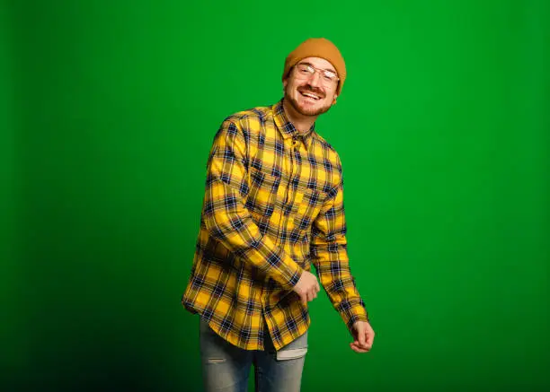 Mid adult hipster man dancing infront of a green studio background.