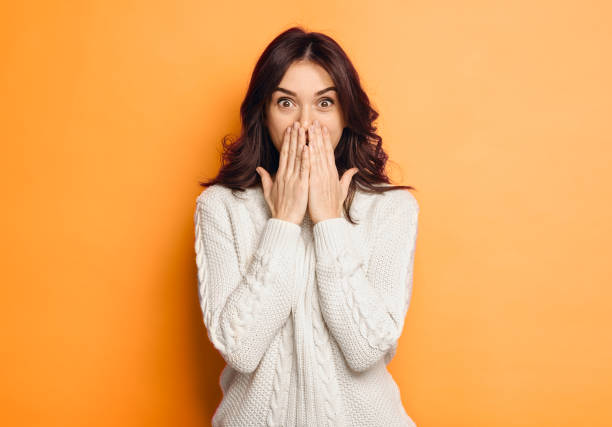 amazed young woman over orange background