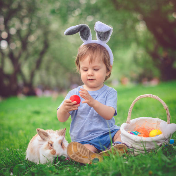 Happy little boy playing with bunny in park on Easter egg hunt