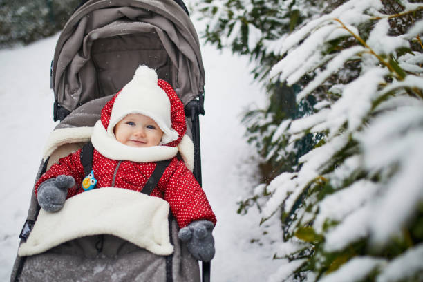 Baby girl in stroller in Paris on a day with heavy snow Happy smiling baby girl in stroller in Paris day with heavy snow. Little kid enjoying the very first snow. Unusual weather conditions in France. baby stroller winter stock pictures, royalty-free photos & images