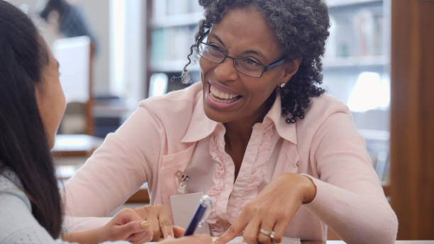istock Volunteer tutor helps elementary schoolgirl with assignment 1124746981