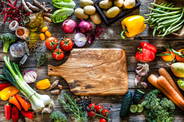 istock Empty cutting board surrounded by fresh vegetables shot from above on rustic wooden table 1124754291