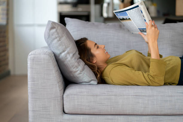 istock Happy woman reading while relaxing at home 1124755483