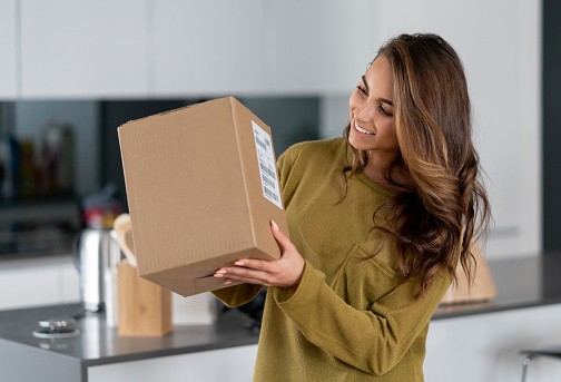 Portrait of a casual woman getting a parcel in the mail at home - lifestyle concepts