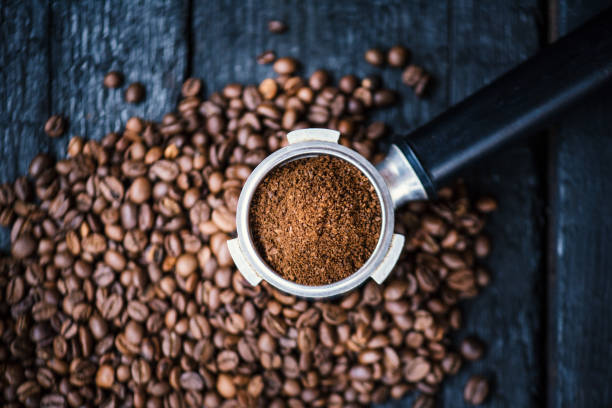 istock Bottomless filter with grind beans on a wooden black table. Roasted coffee beans. Espresso coffee extraction. Prepare of espresso. 1124757597
