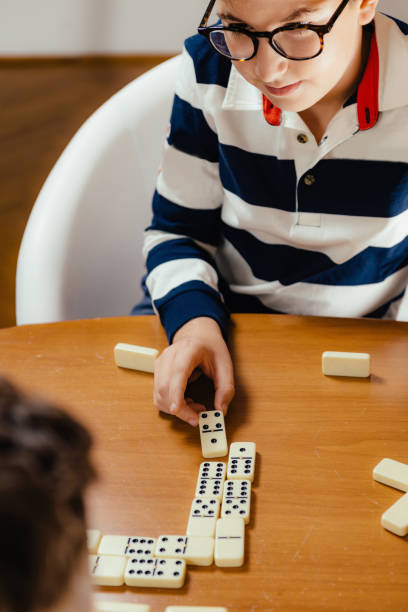 istock Boy Playing Dominoes At Table In Home 1124759824